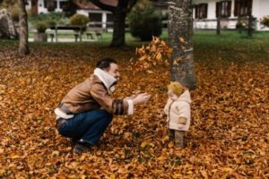 dad and girl playing in leaves